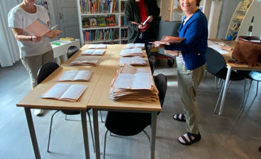 en gruppe mennesker som står rundt et bord med bøker på