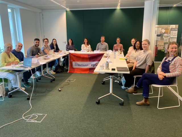 en gruppe mennesker som sitter ved et hesteskoformet bord