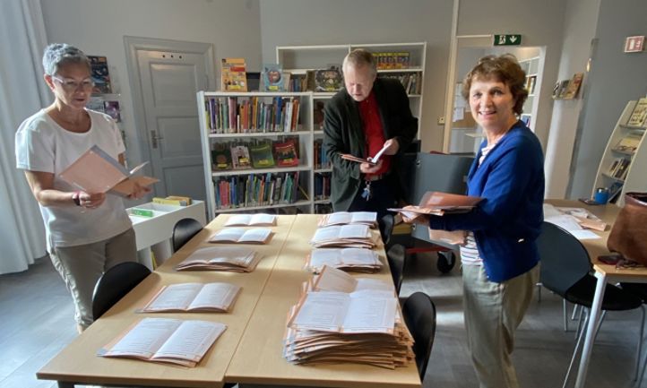 en gruppe mennesker som står rundt et bord med bøker på