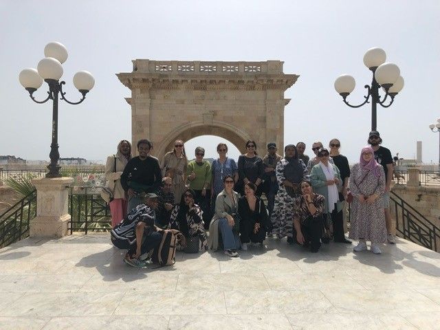 En gruppe mennesker som poserer for et bilde foran en steinbue