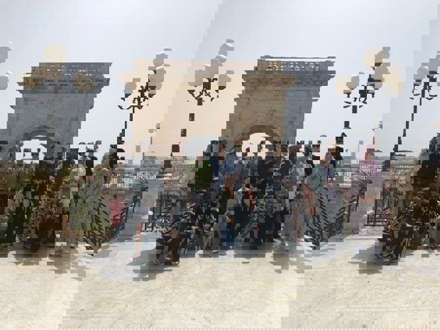 Foto: Gruppebilde fra byvandring En gruppe mennesker som poserer for et bilde foran en steinbue