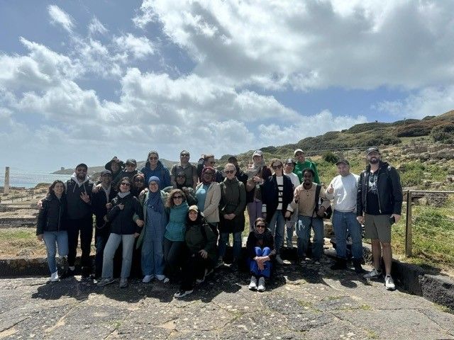 En gruppe mennesker som poserer for et bilde, utsikt til havet