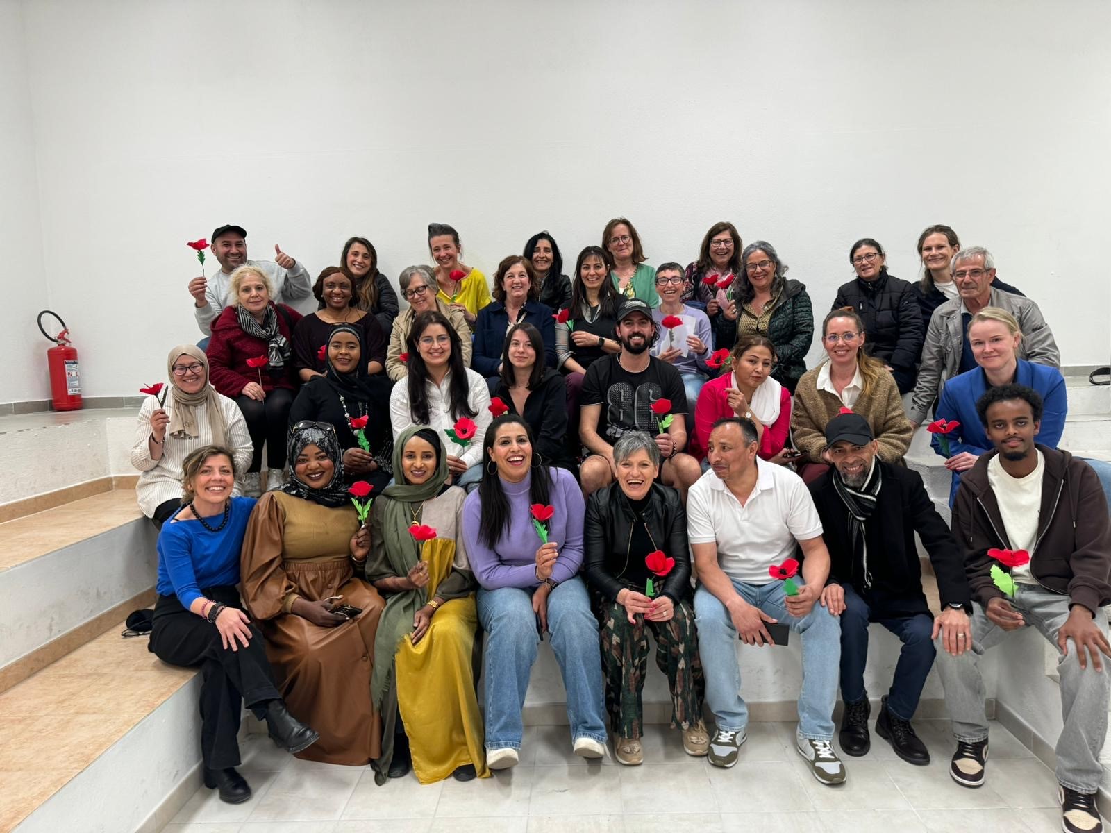 En gruppe mennesker som holder opp hver sin røde blomst mens de poserer for et bilde