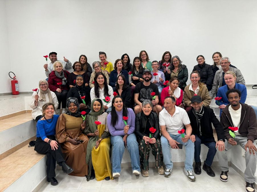 Foto: Siste kveld En gruppe mennesker som holder opp hver sin røde blomst mens de poserer for et bilde