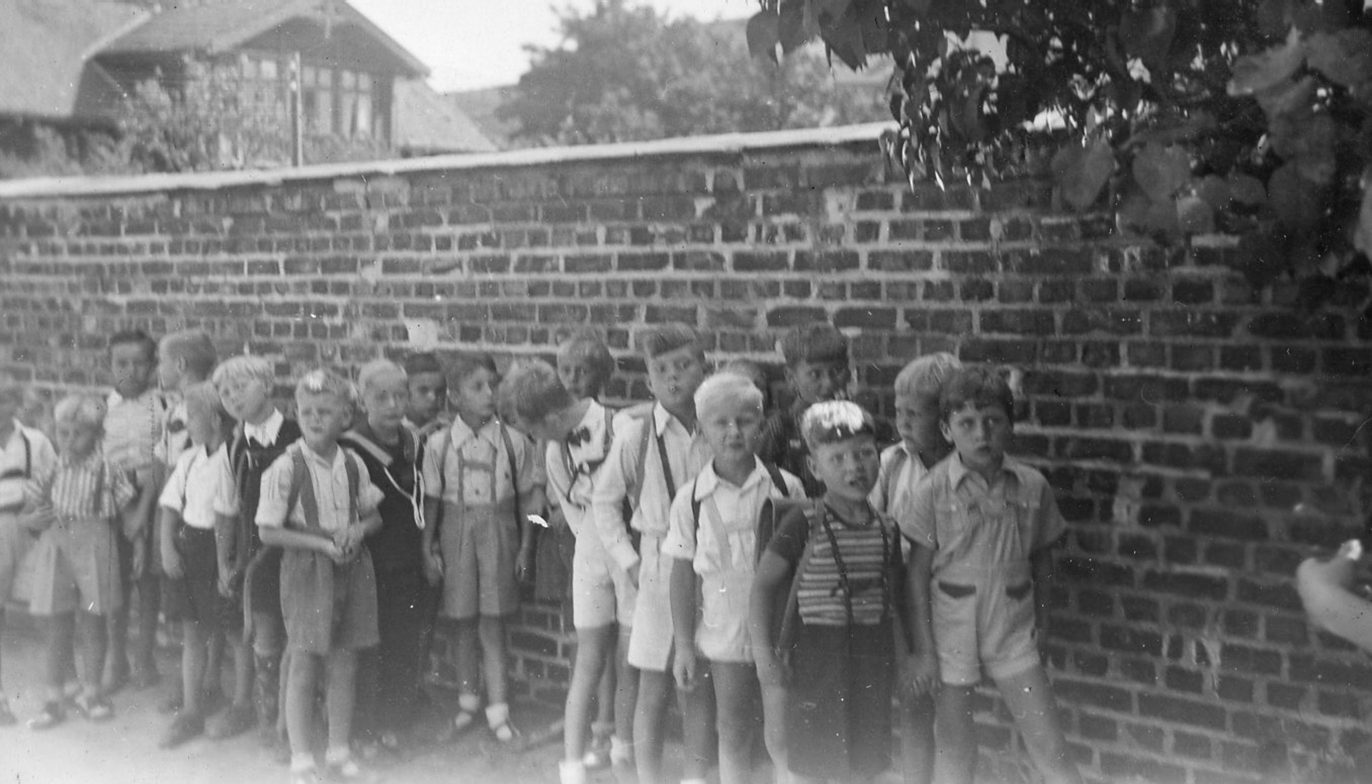 Bilde av 7 år gamle gutter i 1947 som venter på første skoledag ved muren i Dynekilgata