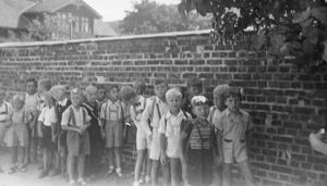 Bilde av 7 år gamle gutter i 1947 som venter på første skoledag ved muren i Dynekilgata