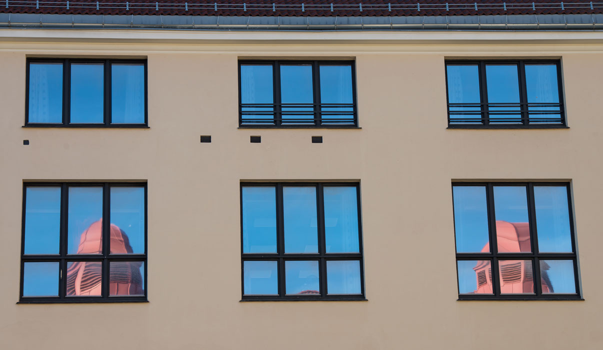Bilde av vinduer i Dynekilgata, der man kan se speilbilde av piper fra taket