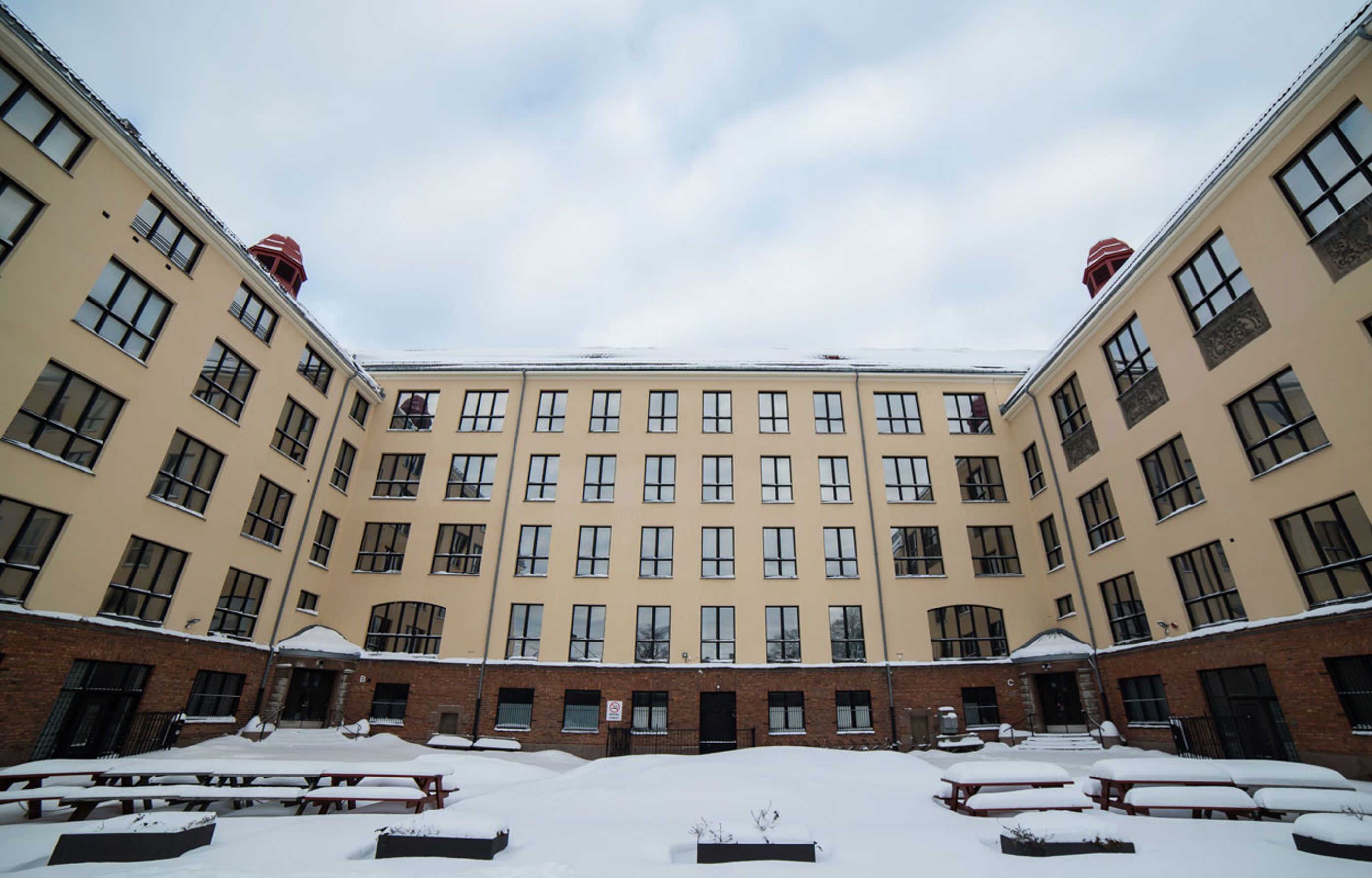 Bilde av Dynekilgata 10 med skolegården i front. Det er mye snø på bord og benker.