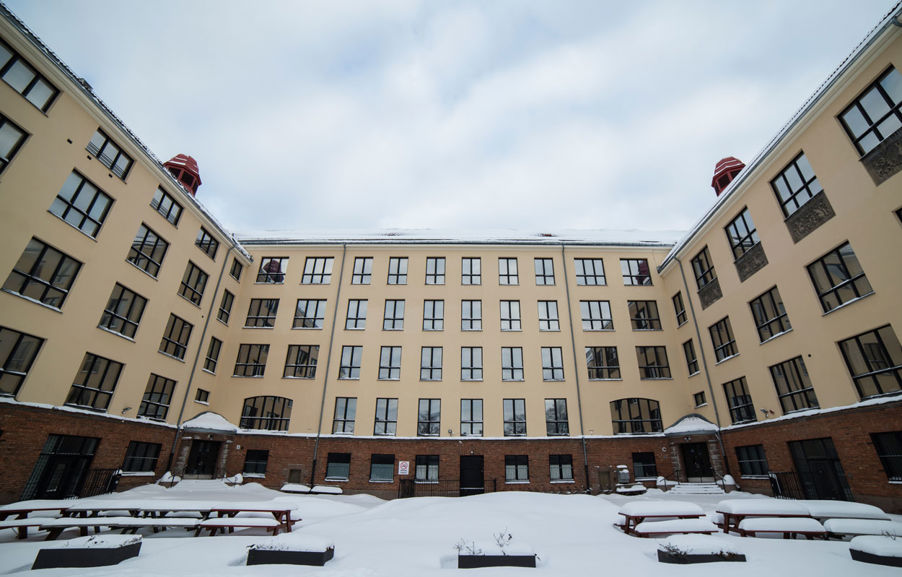 Foto: Skolegården dekket av snø. Bilde av Dynekilgata 10 med skolegården i front. Det er mye snø på bord og benker.
