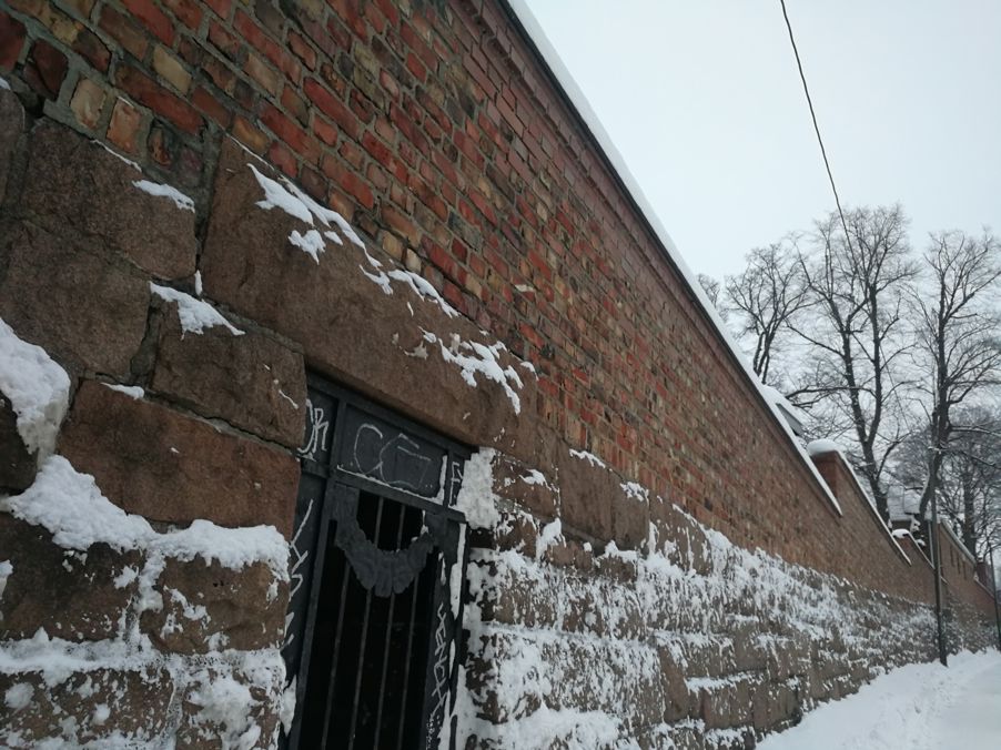 Foto: Muren i Dynekilgata Bilde av muren langs skolegården i Dynekilgata. Muren er i rød murstein og det er snø langs kanten.