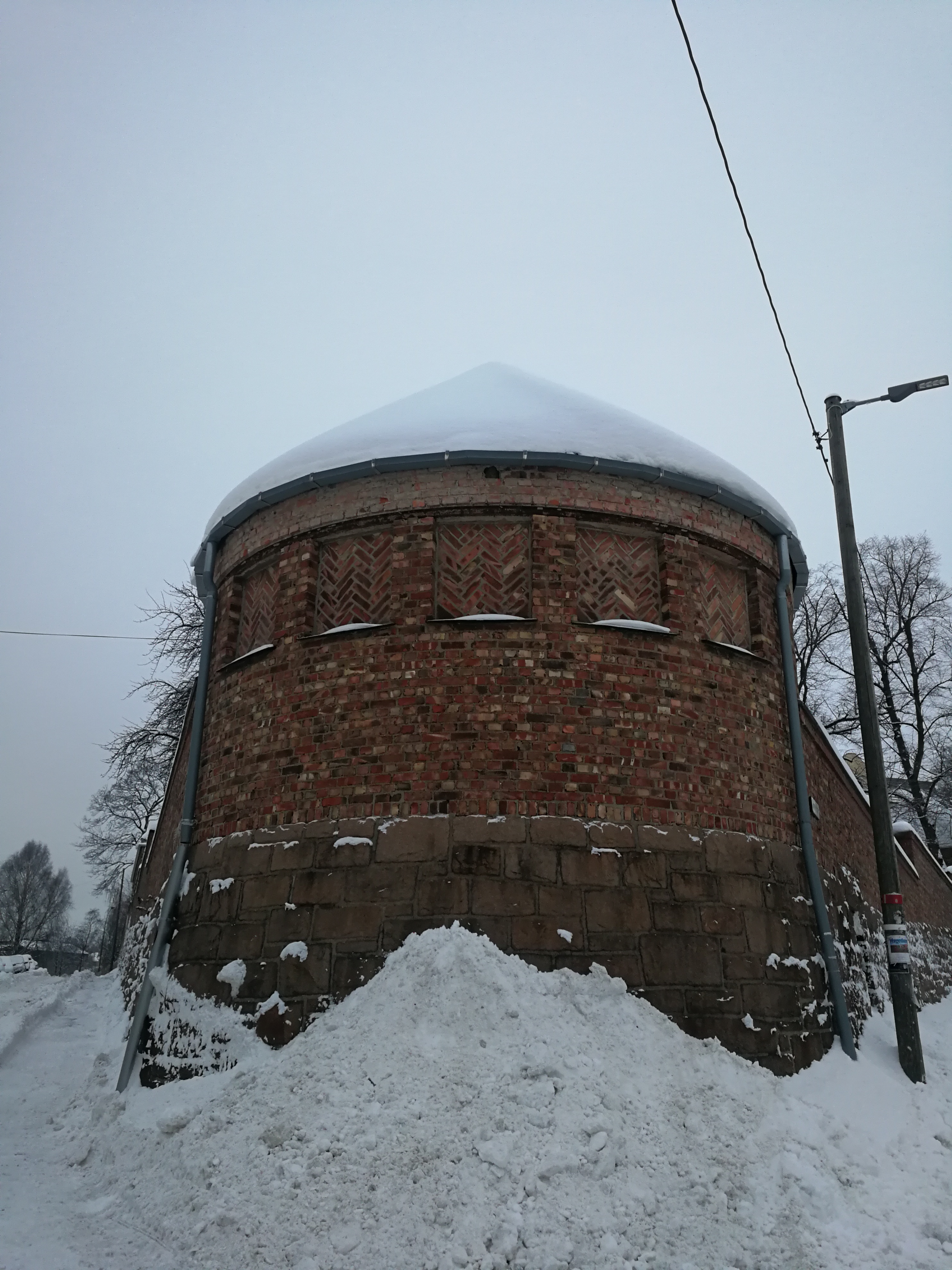 Tårnet i enden av skolegården i Dynekilgata 10. Det er i rød murstein og det er mye snø foran.